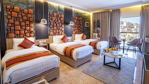 Une chambre d’hôtel avec trois lits, un coin salon avec une table et une vue sur la ville.