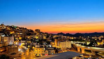 A cityscape at dusk with illuminated buildings and a bridge.