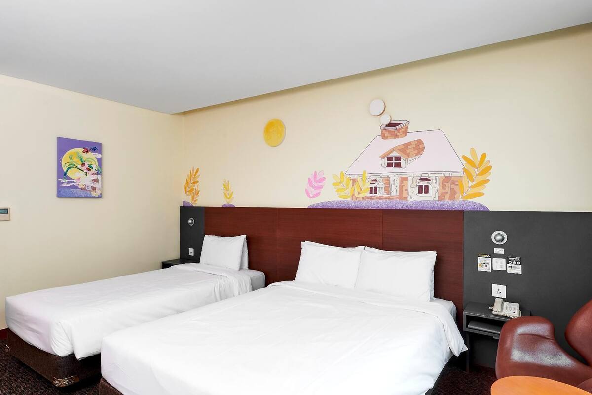 Hotellihuone, jossa on kaksi sänkyä, puinen pääty, seinämaalaus ja työpöytä, jossa on puhelin.