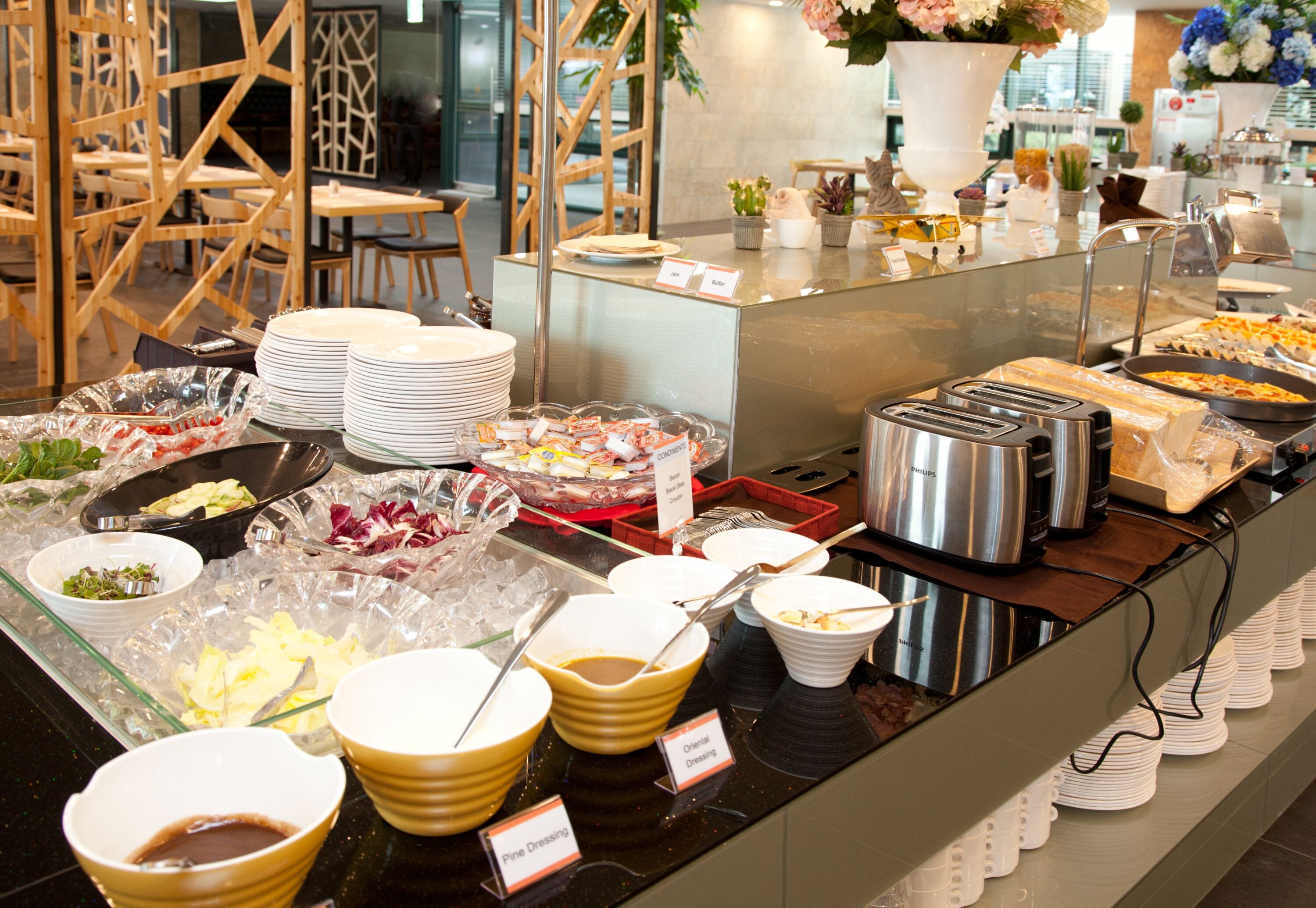 A buffet with various food items and condiments, including bowls of salad, sandwiches, and a variety of desserts.