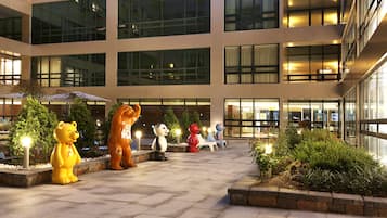 A building with multiple floors, large windows, and outdoor seating areas with decorative animal statues.