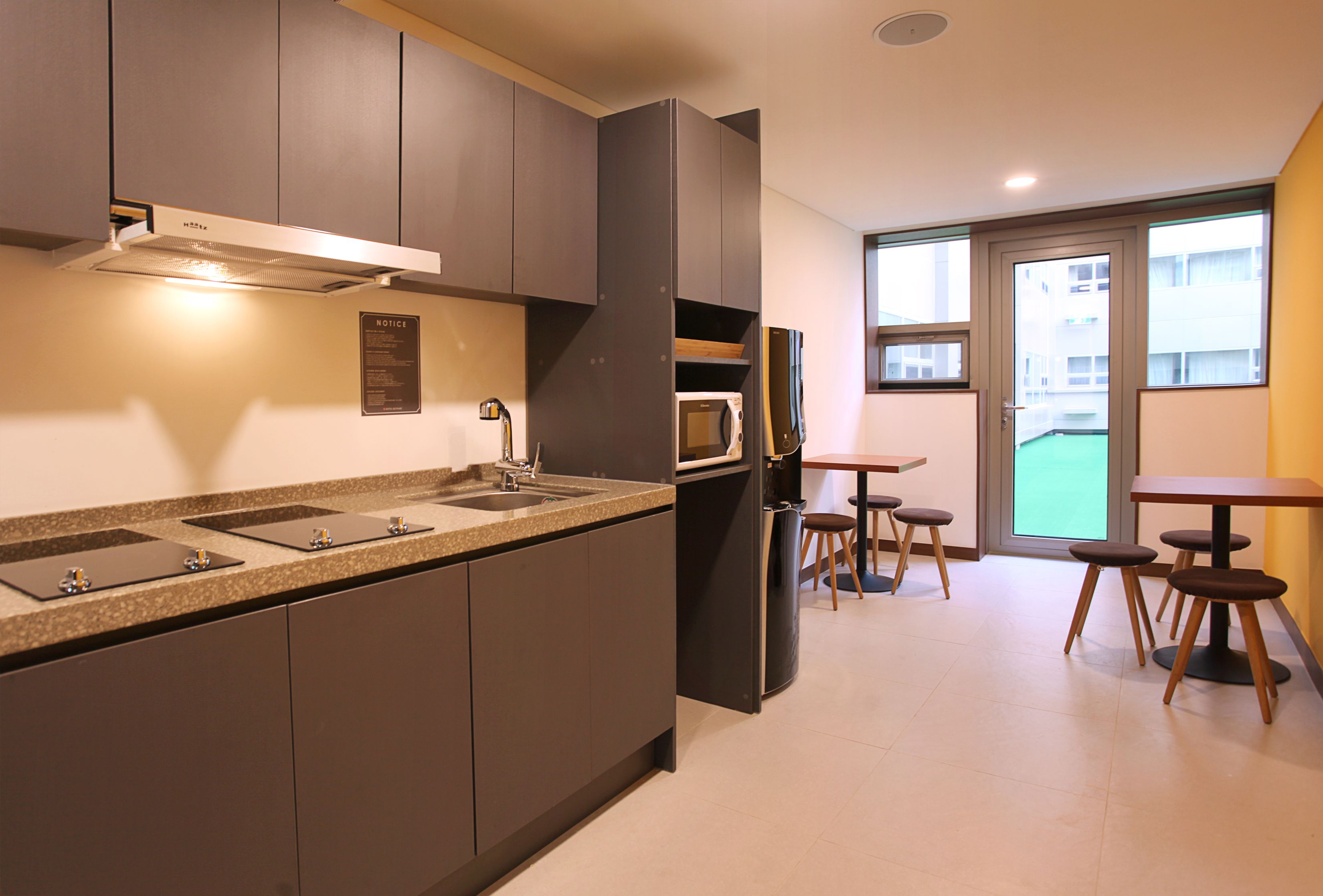 Una cocina moderna con microondas integrado, pileta doble y un comedor con taburetes.