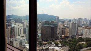 A cityscape with high-rise buildings, a prominent tower, and a hilly background.