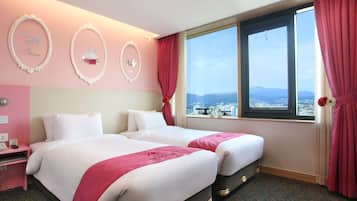 Una habitación de hotel con dos camas, un escritorio y una ventana con vista a la ciudad.
