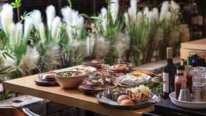 A buffet table with various dishes, a bottle of wine, and condiments. - Hotel Skypark Kingstown Dongdaemun (Seoul)