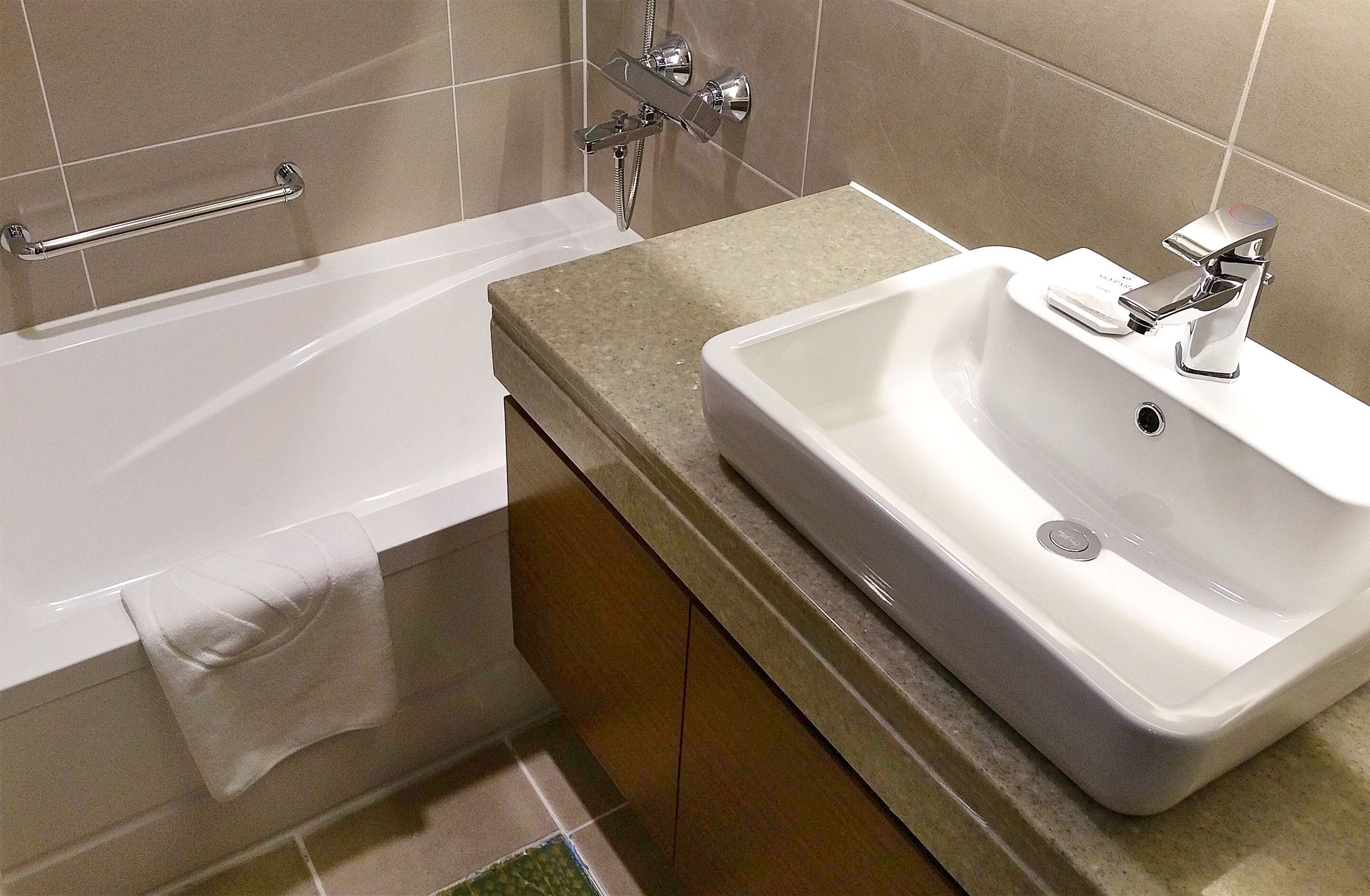A bathroom with a bathtub, a sink, and a towel rack.
