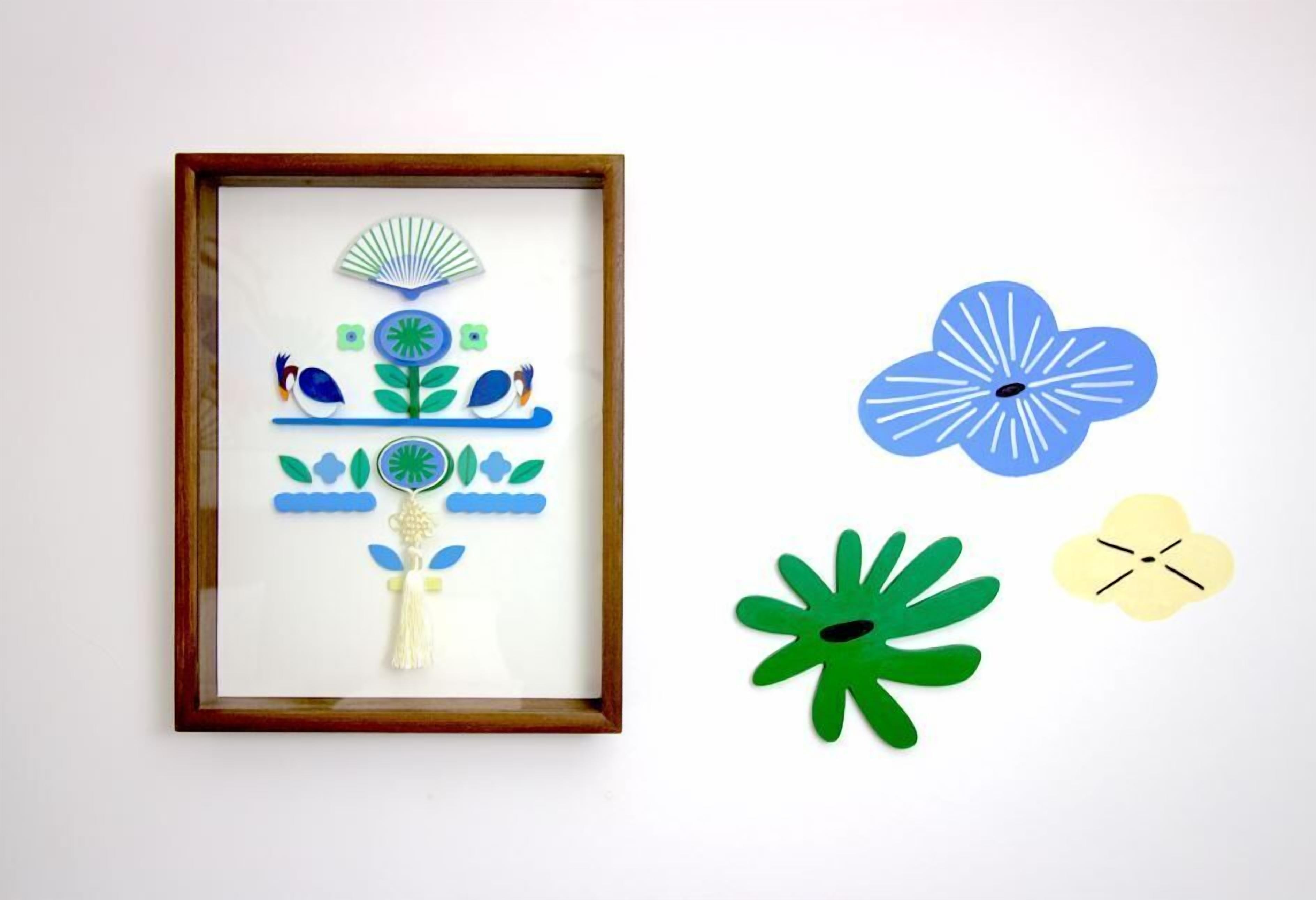 Une œuvre d’art encadrée représentant un oiseau, une plante et un éventail, accrochée à un mur.