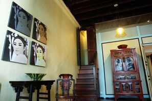 A staircase with a wooden finish, a traditional cabinet with intricate designs, and several framed artworks on the wall. - Coffee Atelier (George Town)