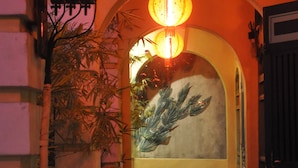 Un comedor interior con mobiliario de mimbre, un farol colgante y un mural en la pared.