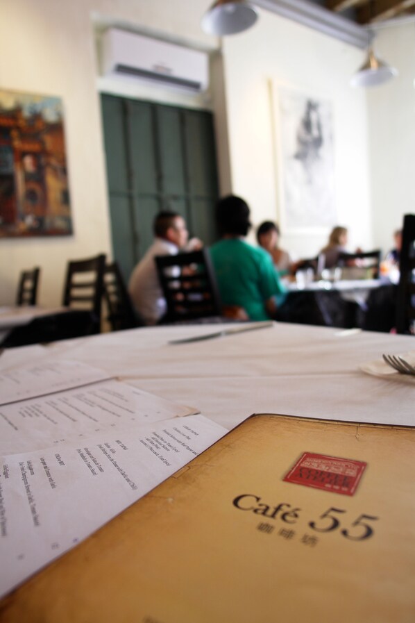 A table with a menu and a sign reading "Café 55". - Coffee Atelier (George Town)