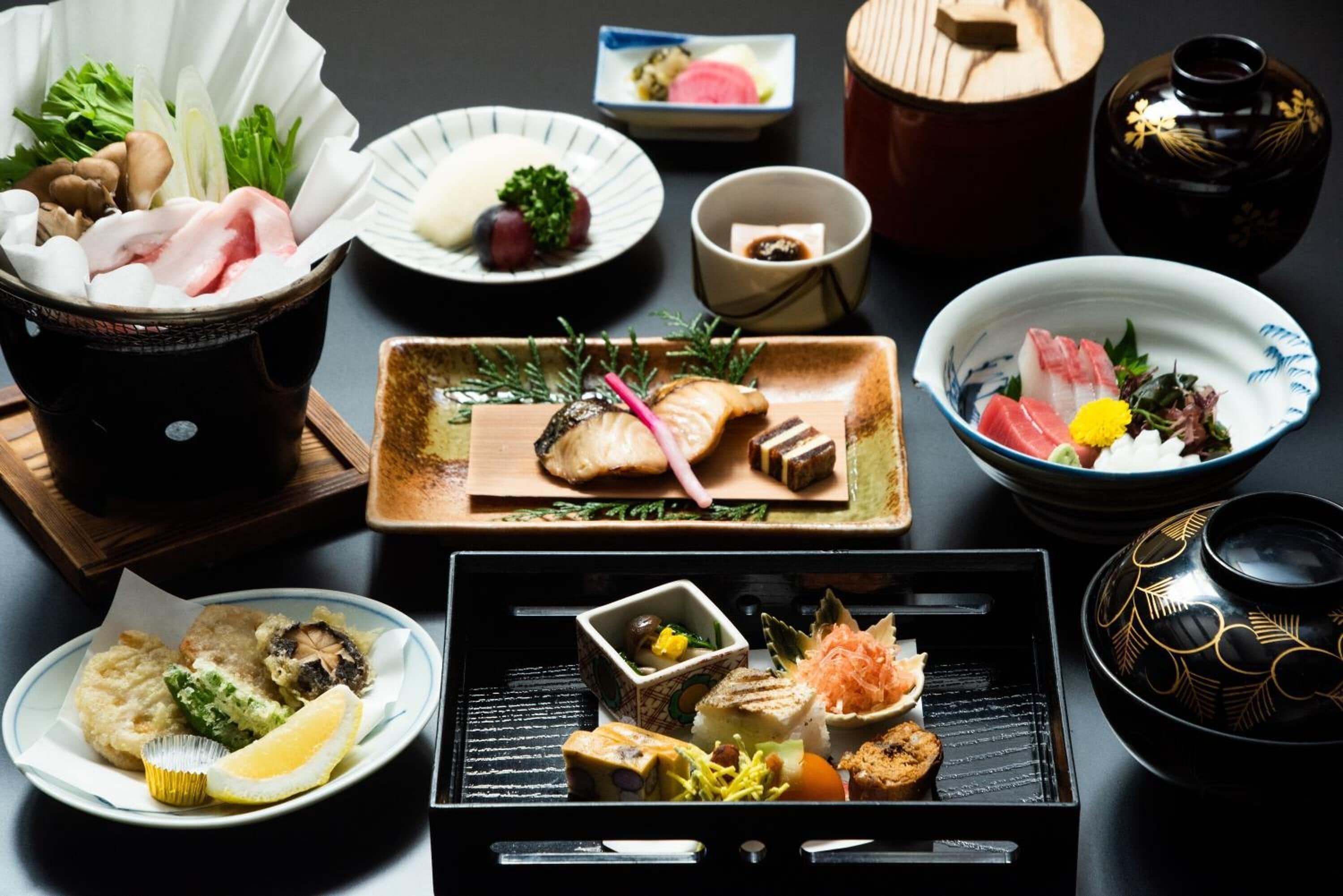 A variety of Japanese dishes, including sushi, sashimi, and tempura, arranged on a table.