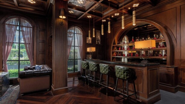 A bar area with a leather sofa, bar stools, and a wine rack. - Metropole, Bangkok, a Tribute Portfolio Hotel (Bangkok)