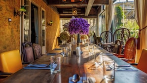 A dining table set with chairs, a chandelier, and a vase of purple flowers. - Metropole, Bangkok, a Tribute Portfolio Hotel (Bangkok)