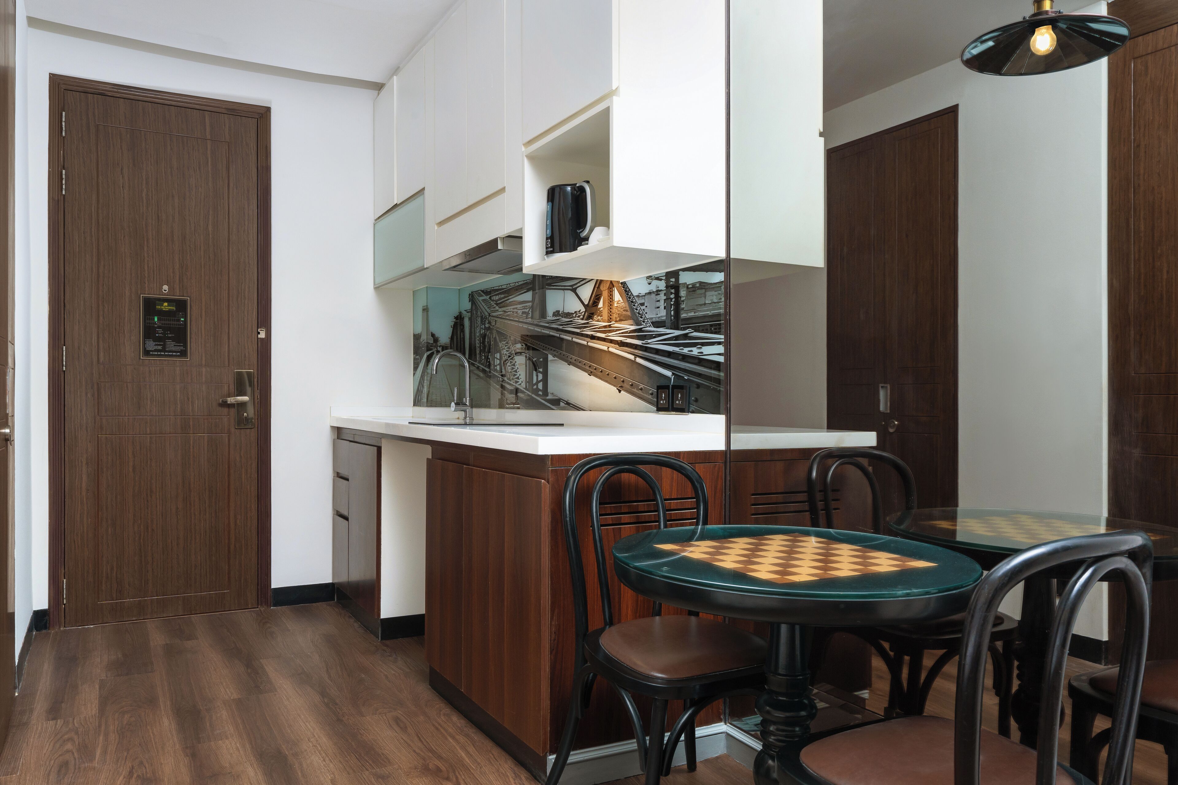 A compact kitchen with a built-in dishwasher, a coffee machine, and a small dining area with a chessboard table.
