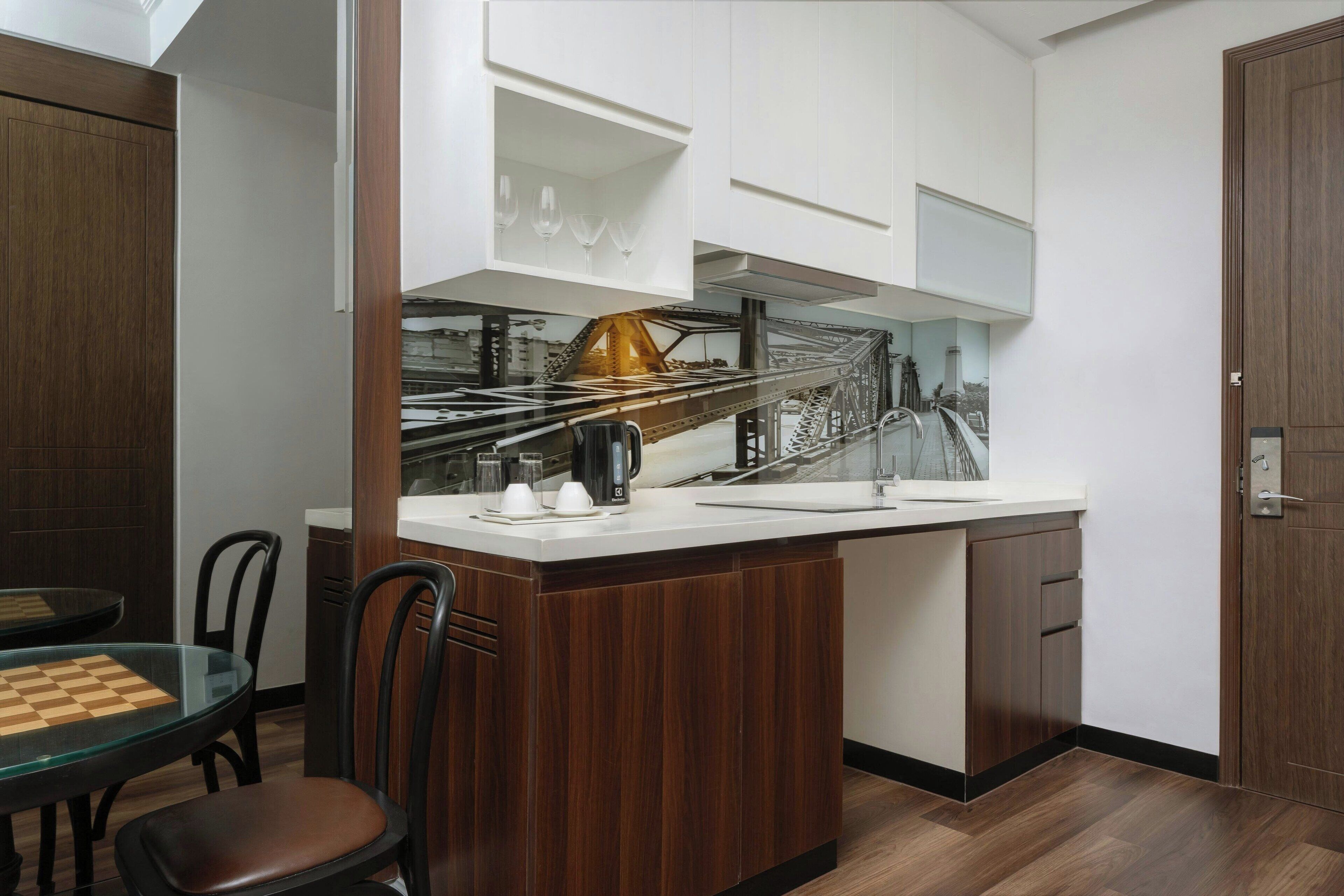 A compact kitchen with a central island, white cabinetry, and a dining area with a glass table and chairs.