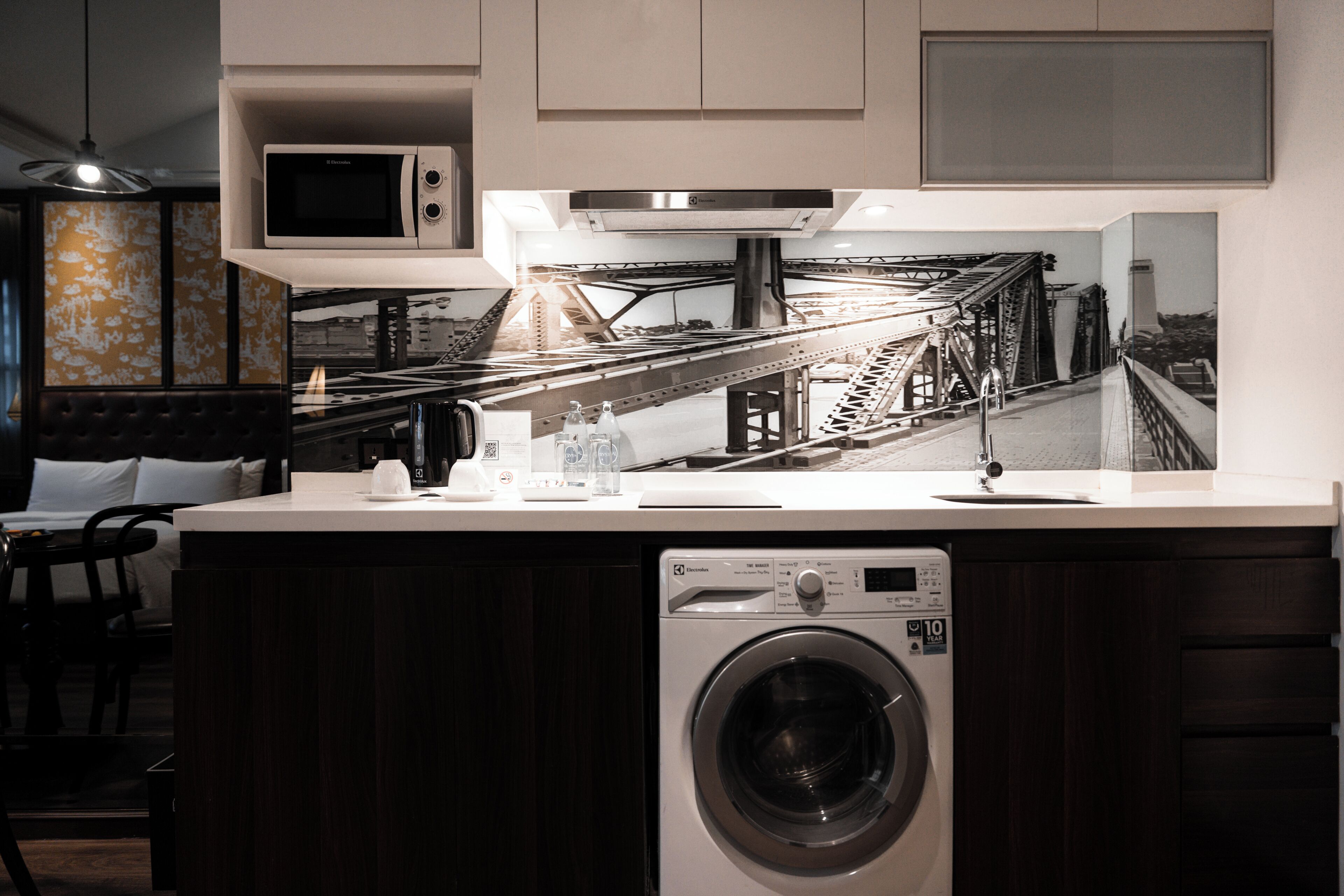 A compact kitchen with a built-in washing machine, a microwave, and a large window with a bridge view.