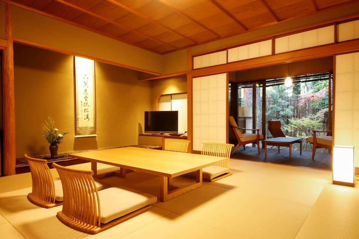 Una habitación al estilo japonés tradicional, con suelo de tatami, una mesa baja y sillas de madera.