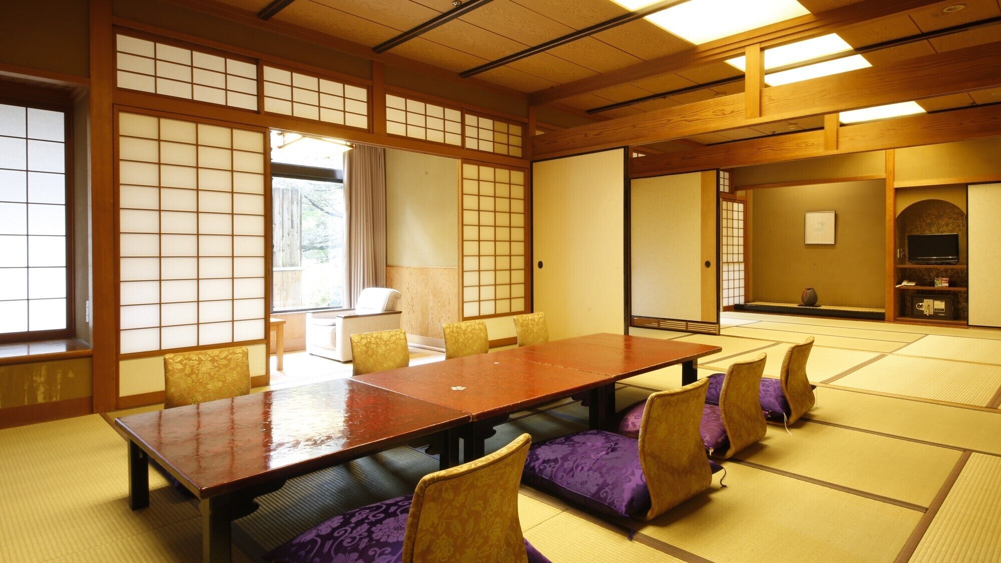 A traditional Japanese-style room with tatami flooring, a wooden table, and purple cushions.