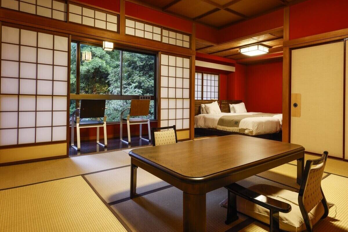 Una habitación japonesa tradicional con suelo de tatami, una mesa baja, una cama y puertas correderas.