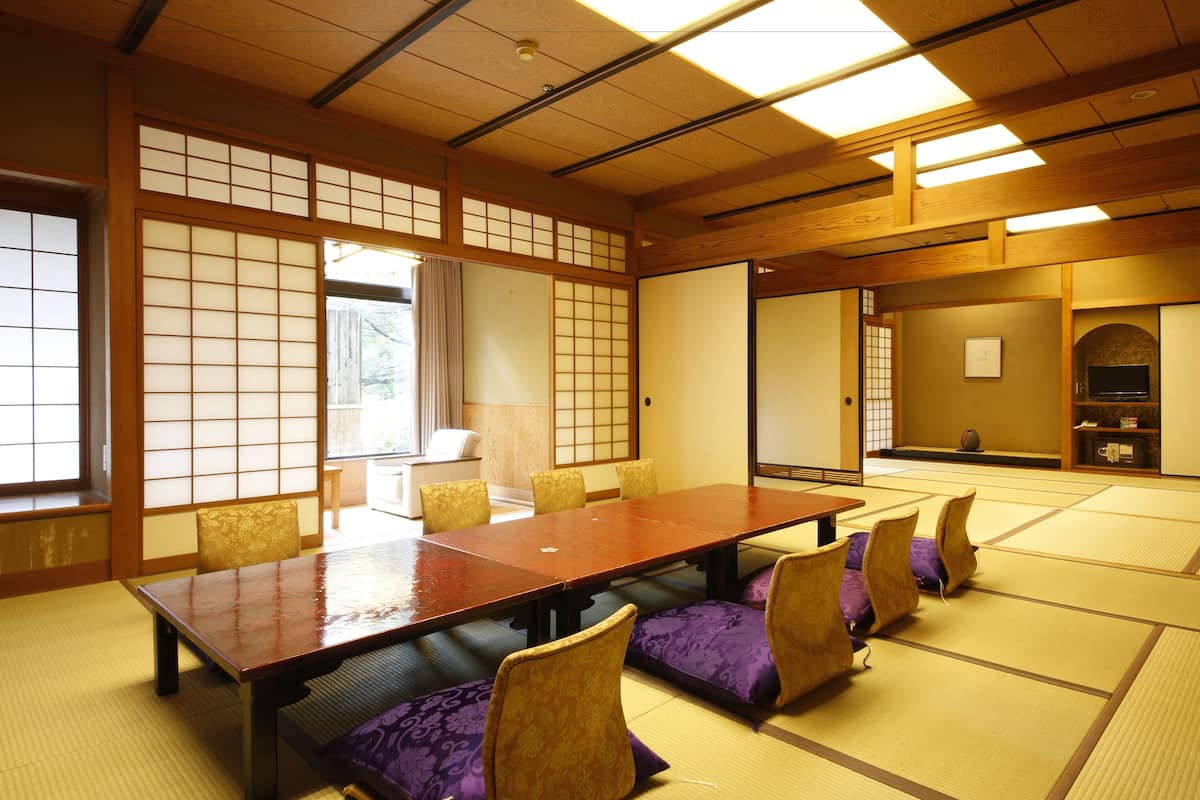 Una habitación japonesa tradicional con suelo de tatami, una mesa baja y cojines morados.