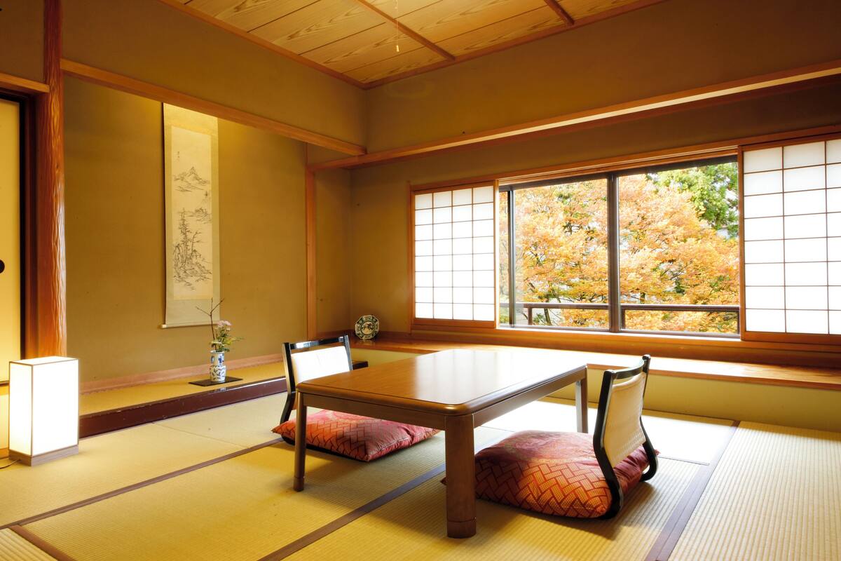 Una habitación japonesa tradicional con suelo de tatami, una mesa baja y biombos de papel.