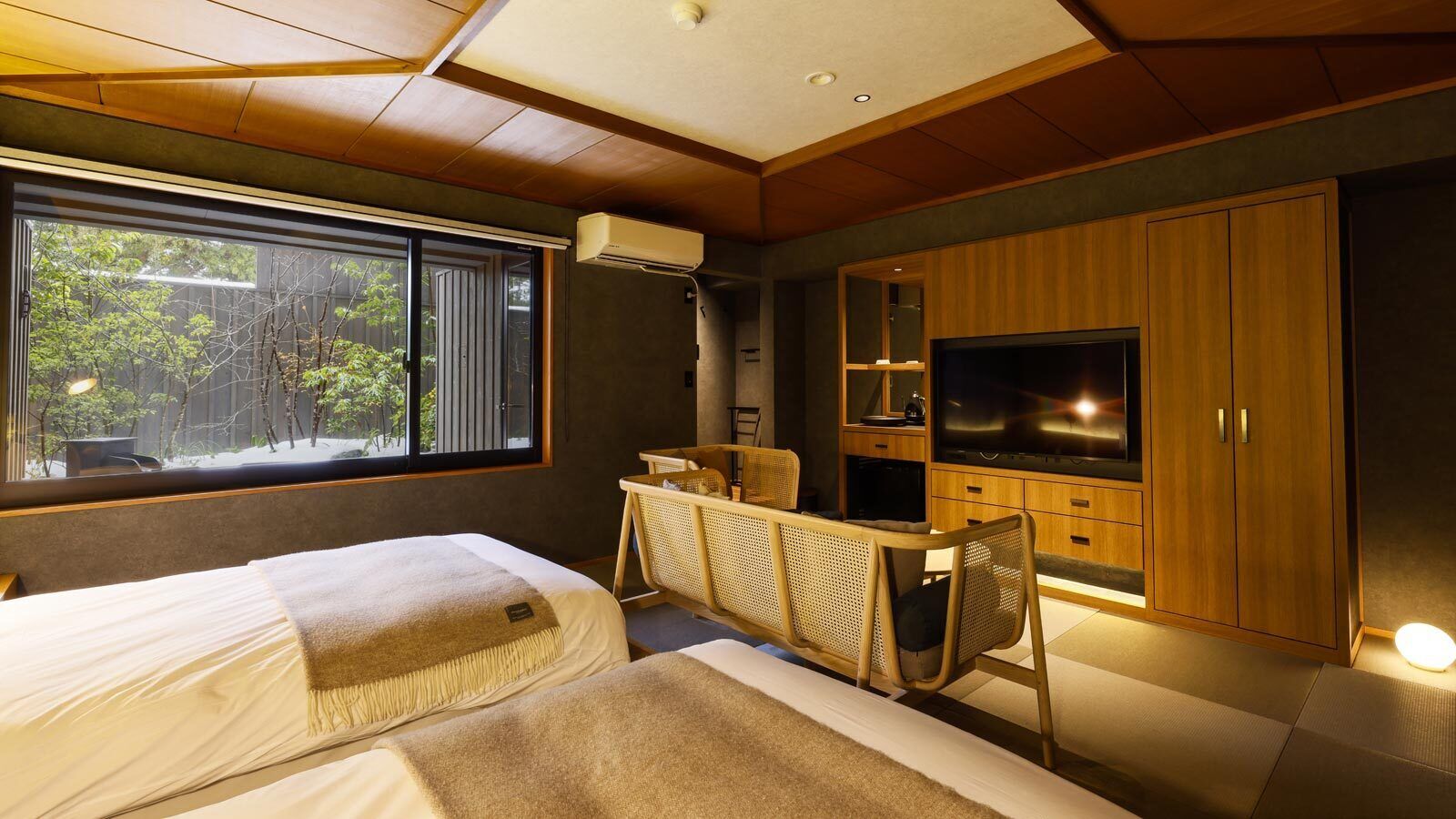 Una habitación de hotel moderna con una cama grande, un escritorio, un televisor y vistas al exterior.