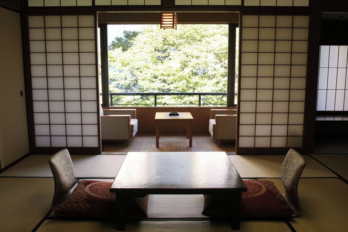 Una habitación japonesa tradicional con suelo de tatami, una mesa baja y vistas a través de un celosón.