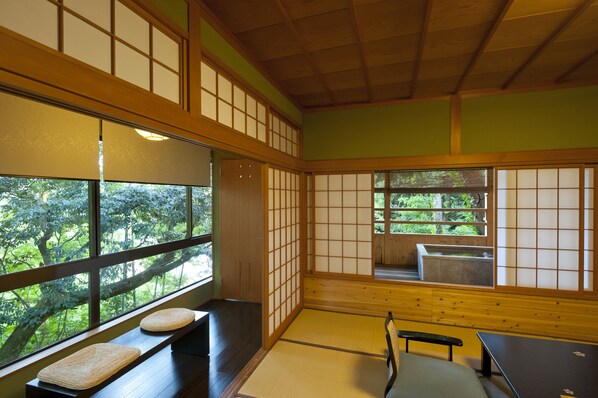 A traditional Japanese room with tatami flooring, sliding doors, and a view of a forest. - Yoshidaya Sannokaku (Kaga)