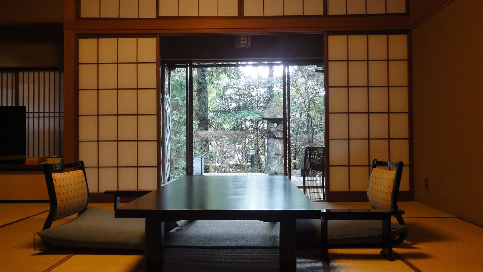 A traditional Japanese room with tatami flooring, a low table, and two chairs.