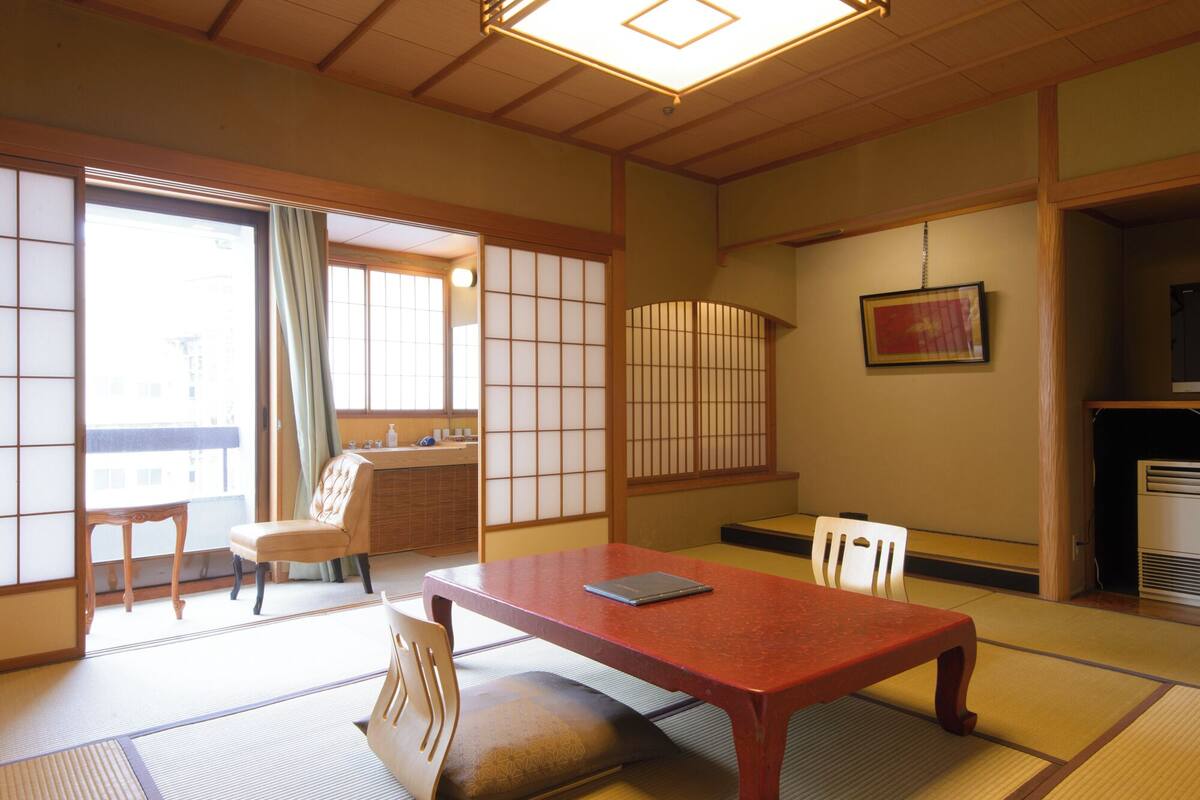 Una habitación japonesa tradicional con suelo de tatami, una mesa baja y puertas correderas.