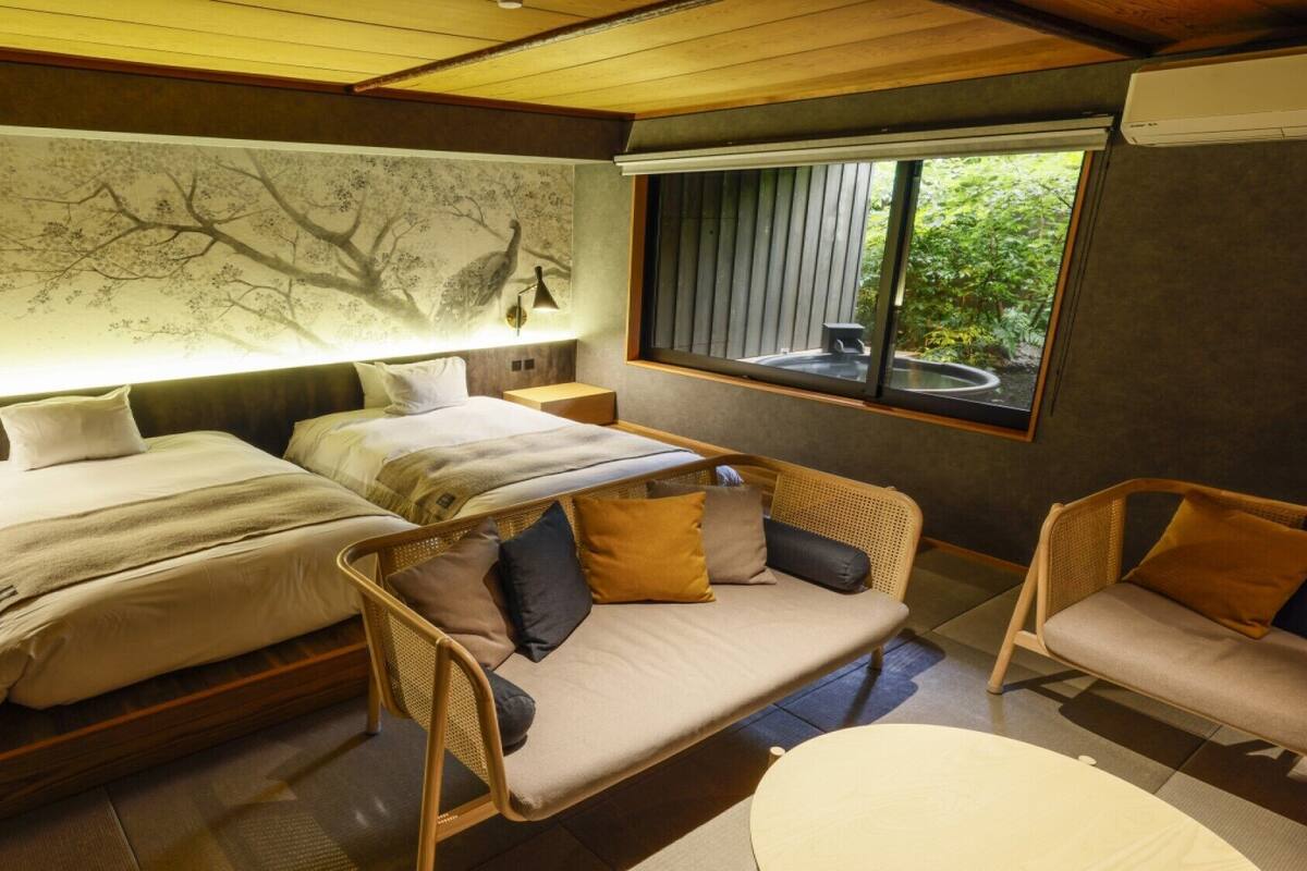 Un dormitorio con dos camas, un sofá y una ventana con vistas a zonas verdes.