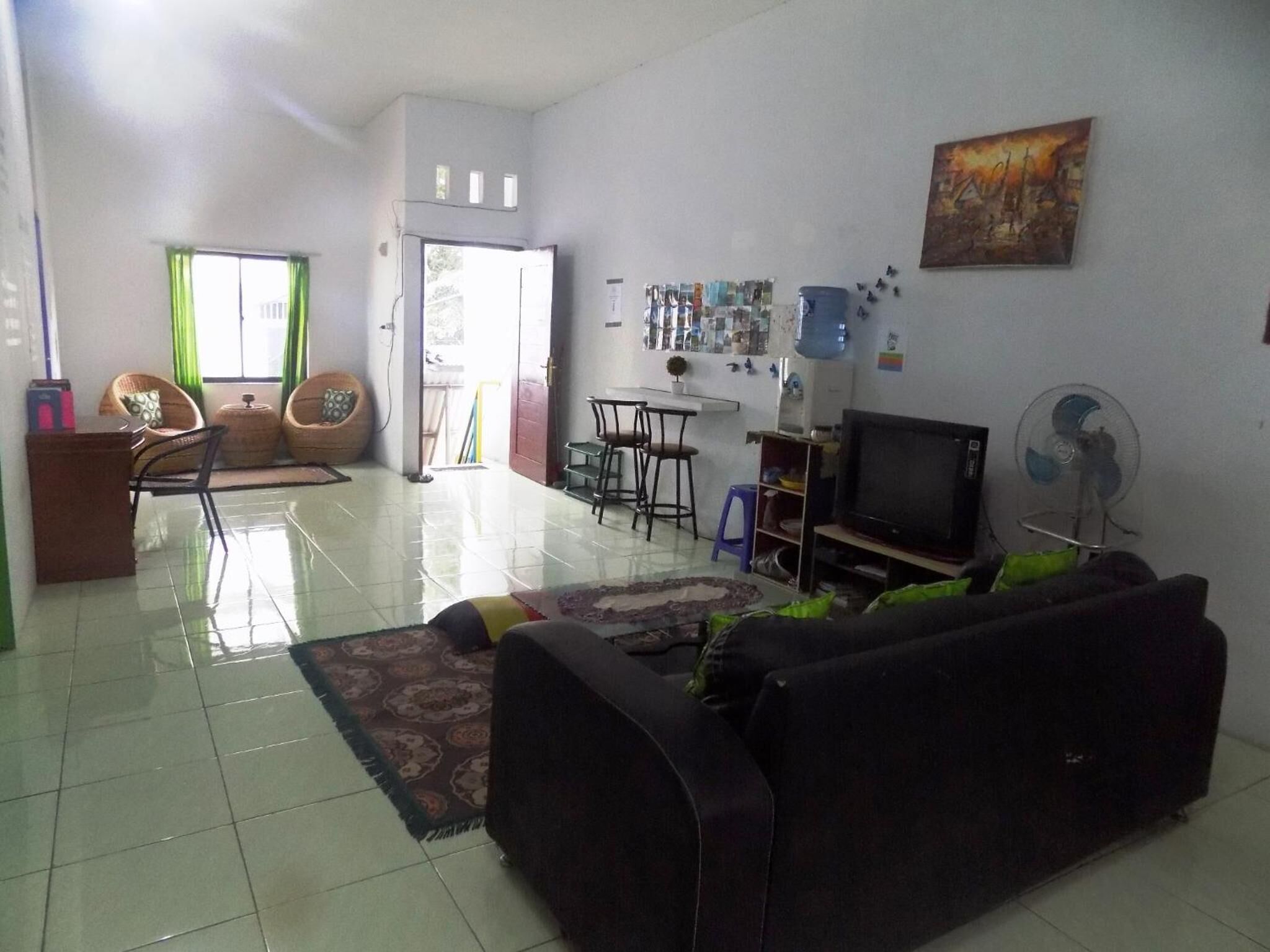 A living room with a sofa, TV, and a water dispenser on the wall.