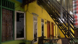A room with a yellow wall, a staircase, and two chairs. - Amelia 2 Guest House (Medan)