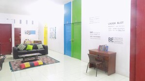 A room with a black sofa, a wooden desk, and a green door. There are motivational posters on the walls. - Amelia 2 Guest House (Medan)