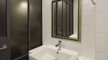 Une salle de bain avec un lavabo blanc, un miroir et un sol carrelé en noir et blanc.