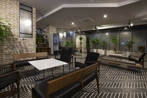 Un área de estar moderna en el interior, con paredes de ladrillo, muebles de madera y plantas en macetas.