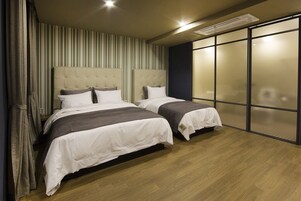 Un dormitorio moderno con dos camas, papel tapiz a rayas y un amplio ventanal corredero.