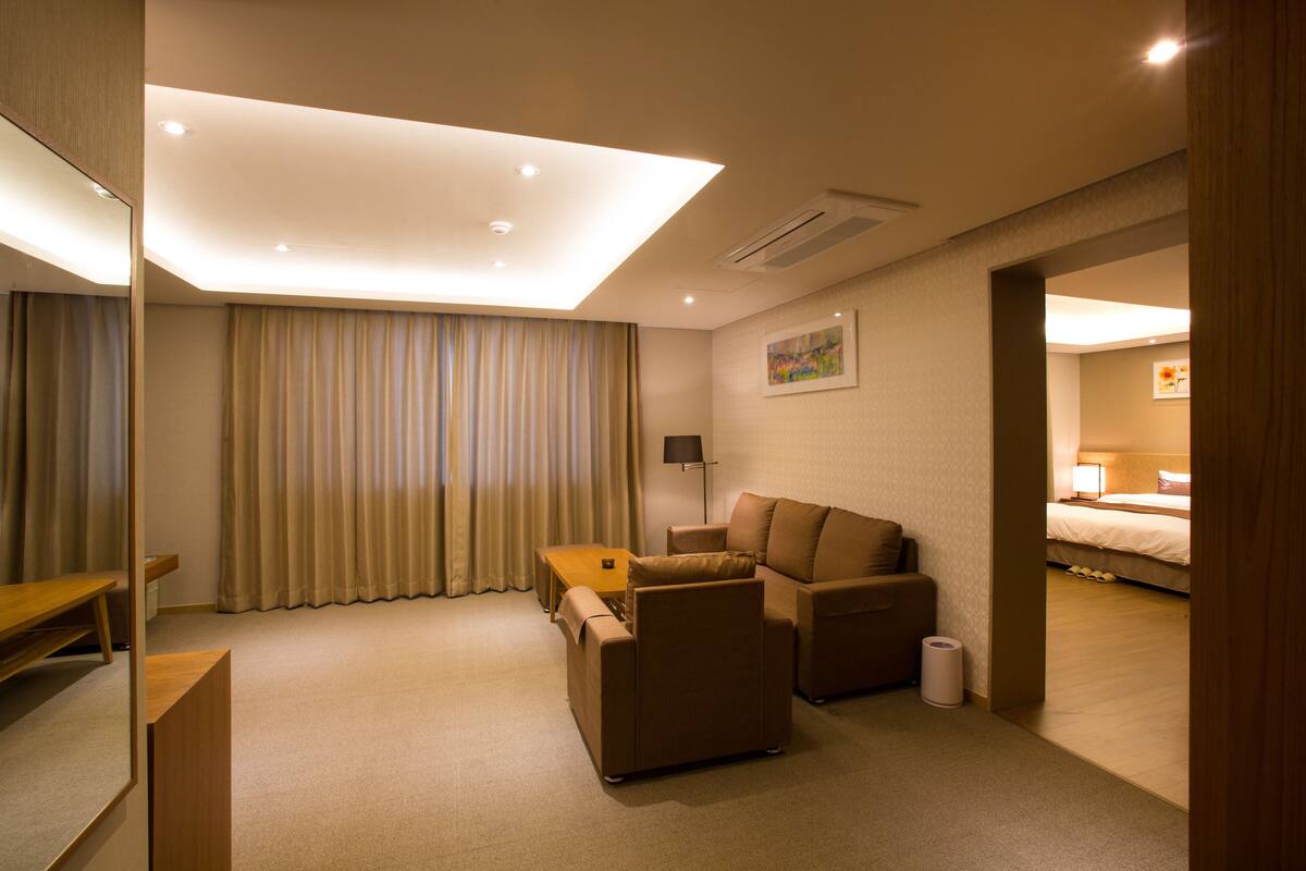Habitación de hotel con sofá, una mesita, lámpara y cama.