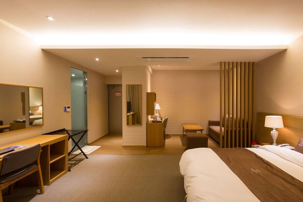 Una habitación de hotel con cama, escritorio, silla y espejo.