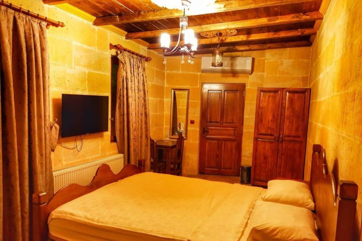 Un dormitorio con una cama grande, cabecera de madera, un televisor de pantalla plana, un armario de madera y un espejo.