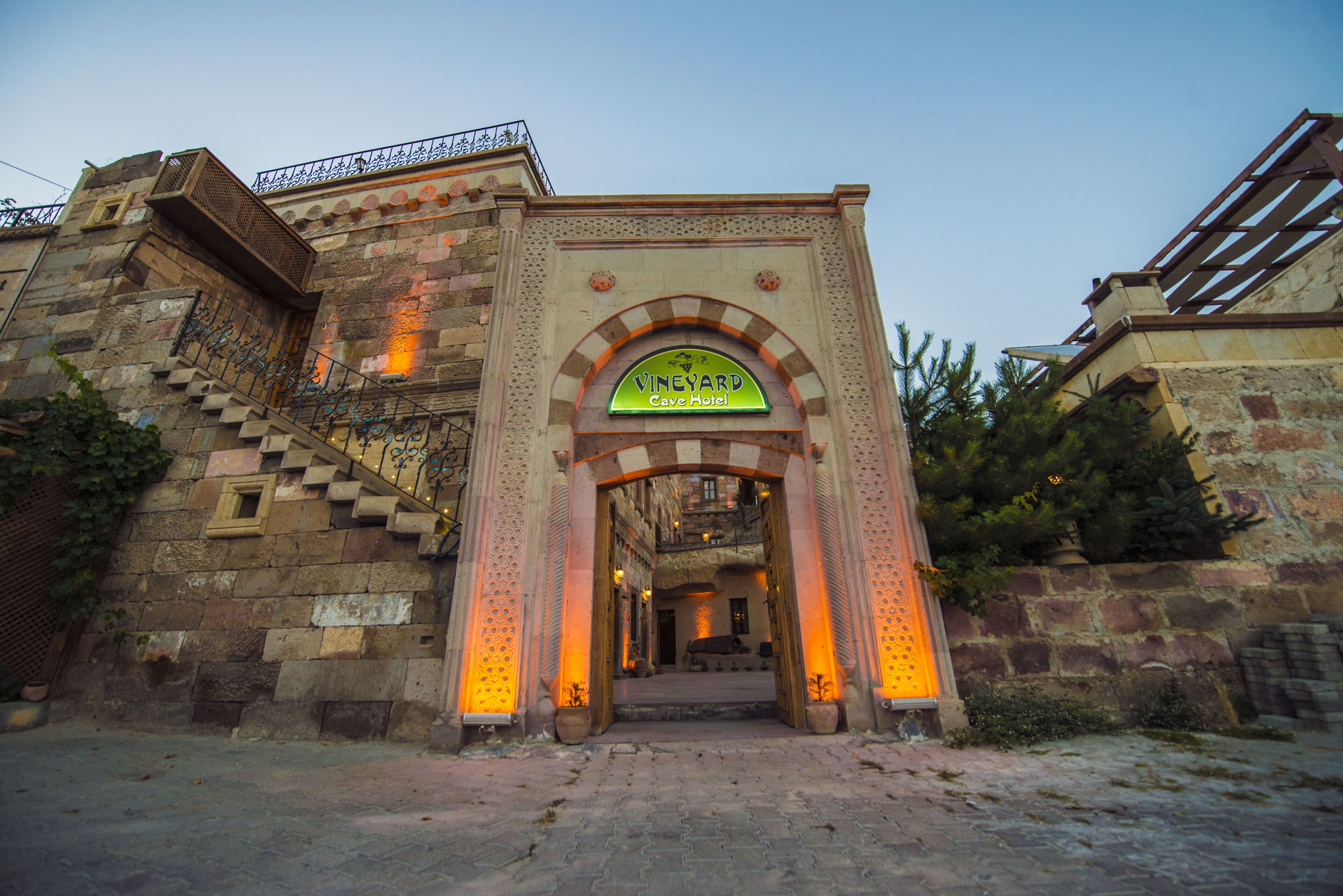 A stone building with a sign reading "VINEYARD Cave Hotel" at the entrance.