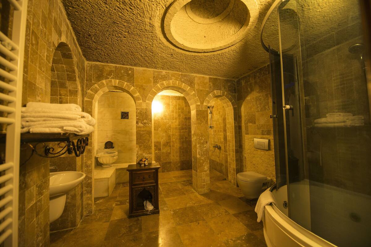 Un baño con bañera, inodoro y lavamanos, que presenta arcos y piso de azulejos.