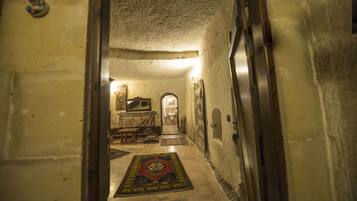 A narrow hallway with a carpet, a mirror, and a door leading to a room.