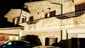 A stone building with a balcony and a car parked in front. - B&B Maremma Nel Tufo (Pitigliano)