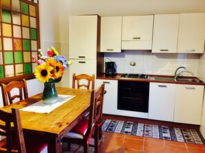 A compact kitchen with white cabinets, a gas stove, and a coffee maker.