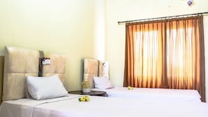 A hotel room with two beds, a nightstand, and a window with curtains. - Lolo Beach Inn (Legian)