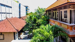 A traditional building with a tiled roof, a balcony with chairs, and a lush green garden area. - Lolo Beach Inn (Legian)