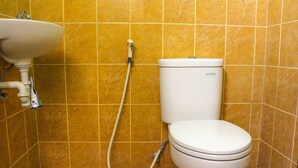 A bathroom with a white sink, toilet, and shower. - Lolo Beach Inn (Legian)