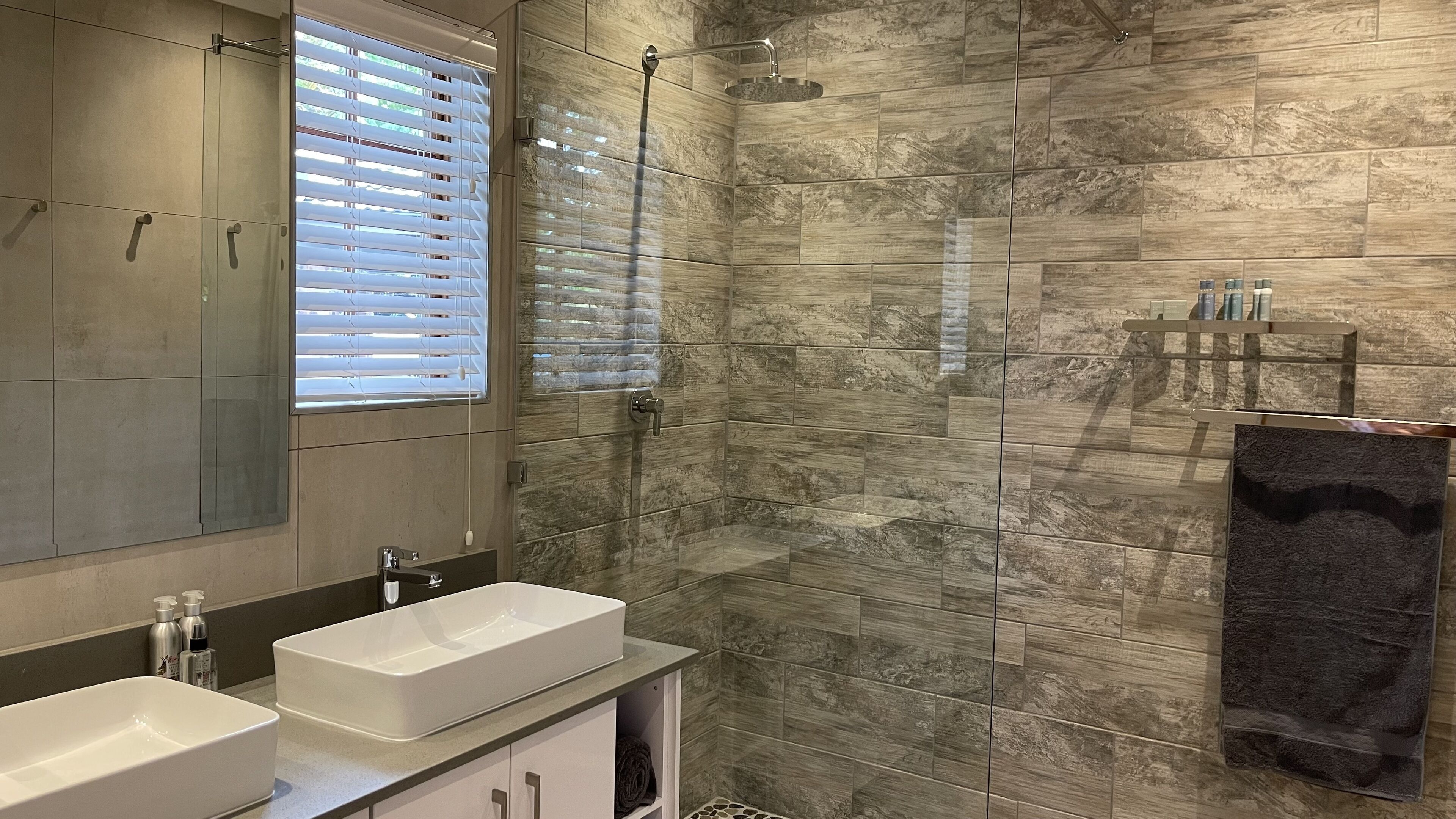 A modern bathroom with a rectangular sink, a shower with a handheld showerhead, and a towel rack.