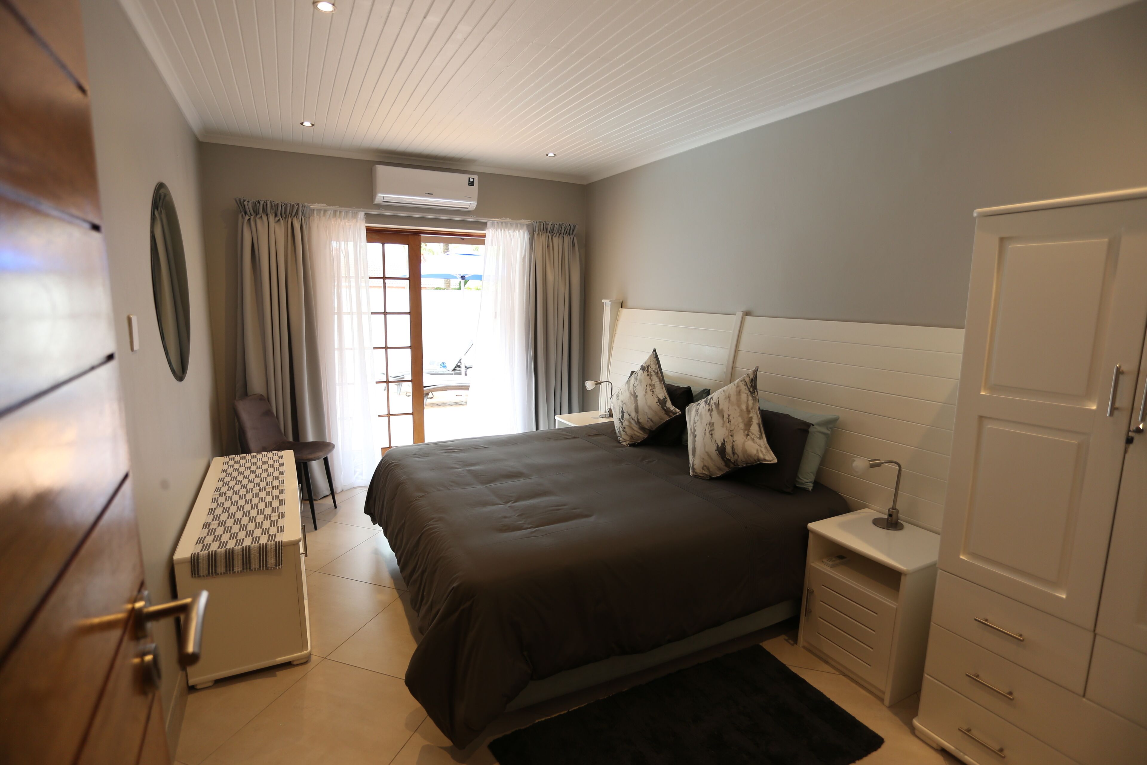 A bedroom with a large bed, bedside tables, a wardrobe, and a desk with a chair.